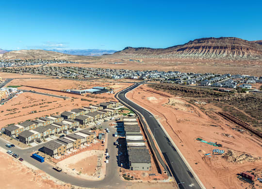 A road curves through a desert-like area with buildings on either side.