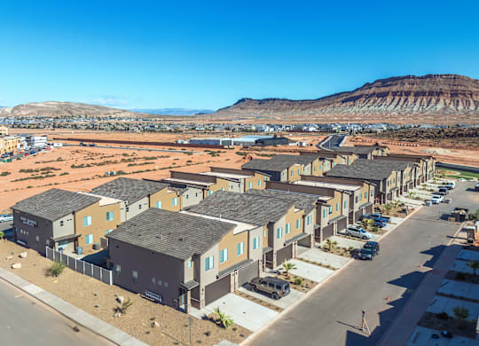 A row of houses in a desert-like area with mountains in the background.