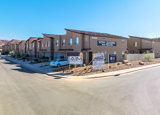 A row of houses with a sign that says "NOW LEASING" in front of them.