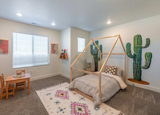 A bedroom with a bed, a table, and a cactus on the wall.