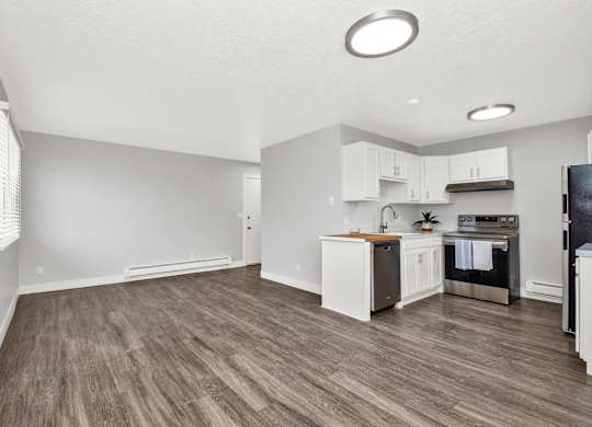A kitchen with white cabinets and a wooden floor.