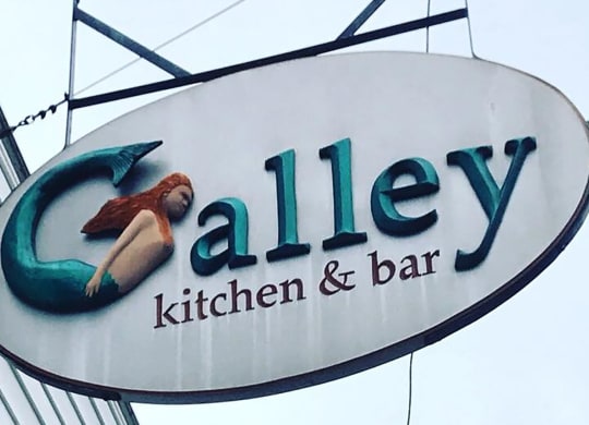 a sign for alley kitchen and bar on a building