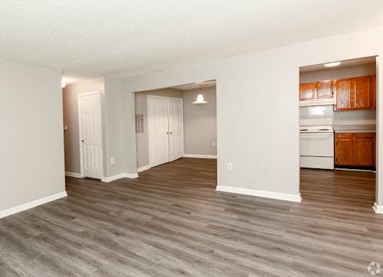 an empty living room and kitchen with white appliances and wood flooring at Avon Crossings, Durham, 27713