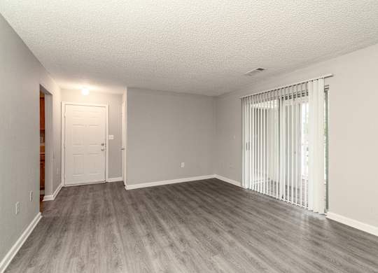 an empty living room with wood flooring and sliding glass doors at Avon Crossings, Durham, NC 27713