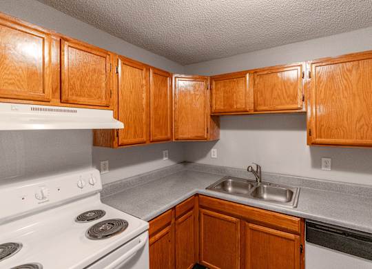 a kitchen with a stove and sink and wooden cabinets at Avon Crossings, Durham