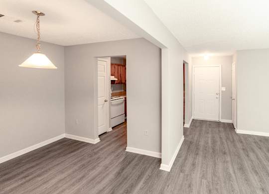 a renovated living room and kitchen with wood flooring and a door to the kitchen at Avon Crossings, Durham, 27713