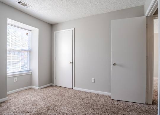 A room with a carpeted floor and two white doors.at Brookside Pointe Apartments, Travelers Rest, SC 29690