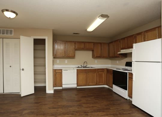 an empty kitchen with white appliances and wooden cabinets at Brookside Pointe, Travelers Rest, South Carolina