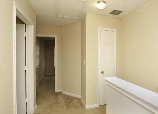 an empty hallway with white walls and a white railing and a door to a closet at Brookside Pointe, Travelers Rest, 29690