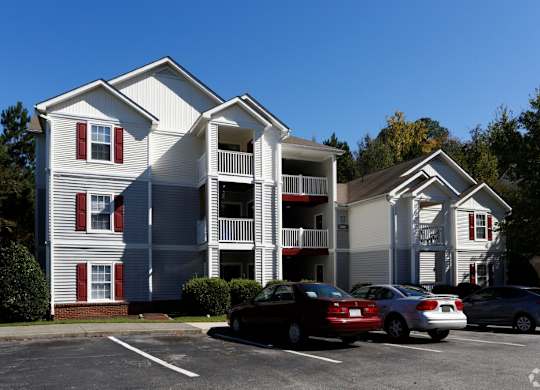an apartment building with cars parked in a parking lot at Avon Crossings, North Carolina   