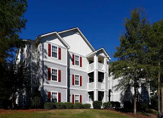 a gray apartment building with red shutters and a blue sky in the background at Avon Crossings, Durham, NC  