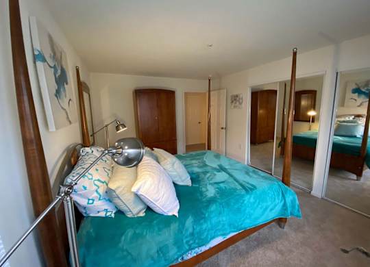 A bedroom with a bed, a lamp, and a mirror.
