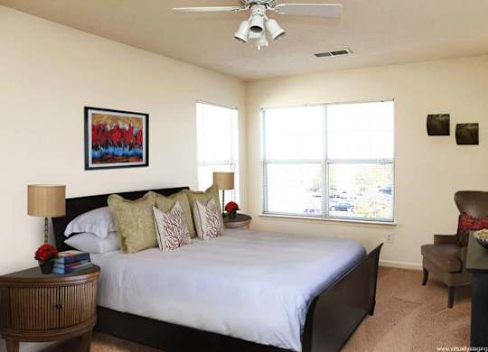 A bedroom with a bed, a chair, and a painting on the wall.