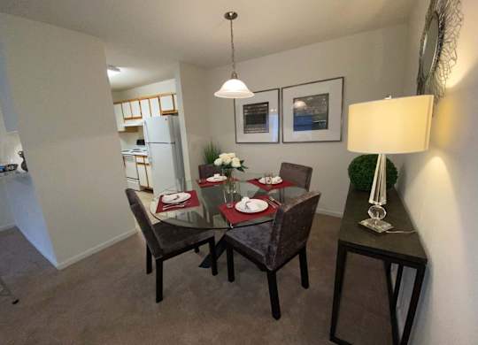 A dining room with a table set for two and a framed picture on the wall.