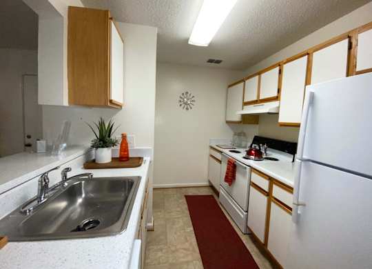 A kitchen with white cabinets and a white fridge.