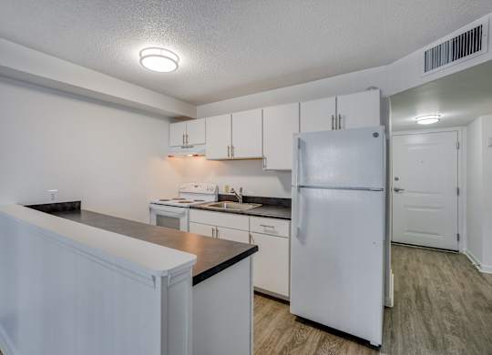 a kitchen with white cabinets and a white refrigerator