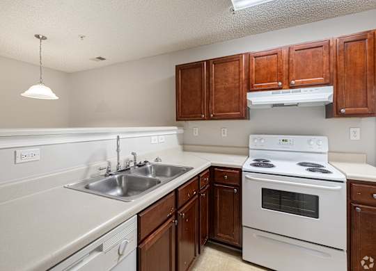 Kitchen with white appliances and wooden cabinets at Cross Creek Apartments, Beaufort, SC, South Carolina, 29906