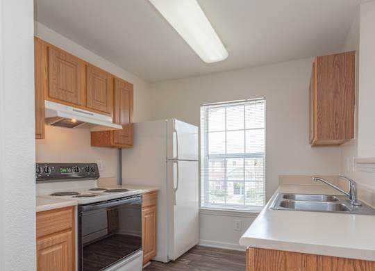 A kitchen with wooden cabinets and a white refrigerator.at The Regency Apartment Homes, Virginia, 20109