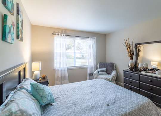 A bedroom with a large bed and a mirror on the dresser.at Bradley Square, North Charleston, 29406