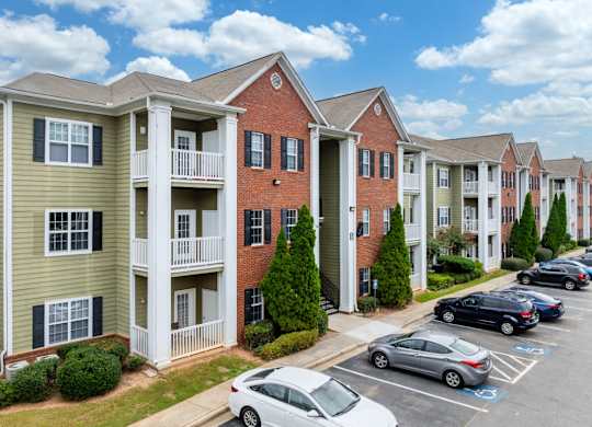 a row of apartment buildings with cars parked in a parking lot at Magnolia Lake Apartments, Carrollton, GA, 30117