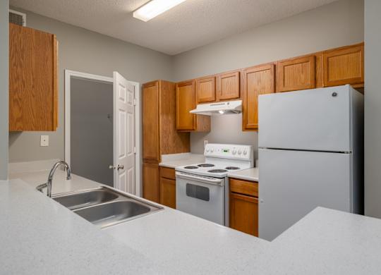 a kitchen with white appliances and wooden cabinets at Magnolia Lake Apartments, Georgia