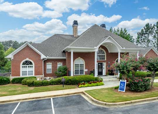 the front of a brick house with a sign in the front yard at Magnolia Lake Apartments, Carrollton, 30117
