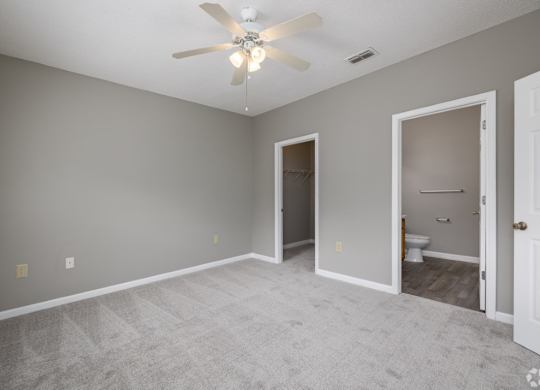 an empty living room with a ceiling fan and a door to a bathroom at Magnolia Lake Apartments, Carrollton