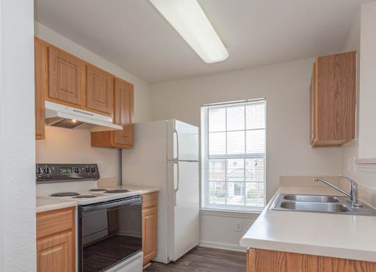 A kitchen with wooden cabinets and a white refrigerator at The Regency Apartment Homes/Broad Pointe, Manassas, Virginia