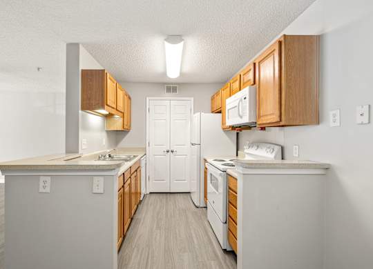 a kitchen with white appliances and wooden cabinets at Palms on Ashley River Apartments, Ladson, SC