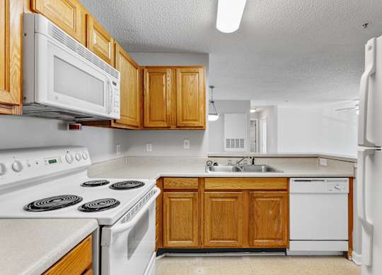 a kitchen with white appliances and wooden cabinets at Palms on Ashley River Apartments, South Carolina 29456