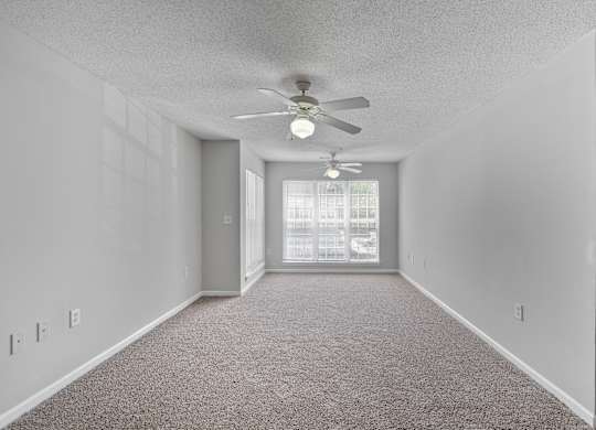 an empty room with a ceiling fan and a window at Palms on Ashley River Apartments, Ladson, 29456