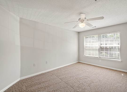 a bedroom with a ceiling fan and a window at Palms on Ashley River Apartments, Ladson, South Carolina