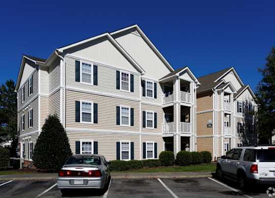 the exterior of an apartment building with cars in a parking lot at Avon Crossings, Durham  