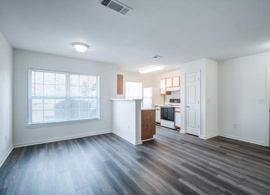 A spacious living room with a kitchenette in the background.at The Regency Apartment Homes, Virginia