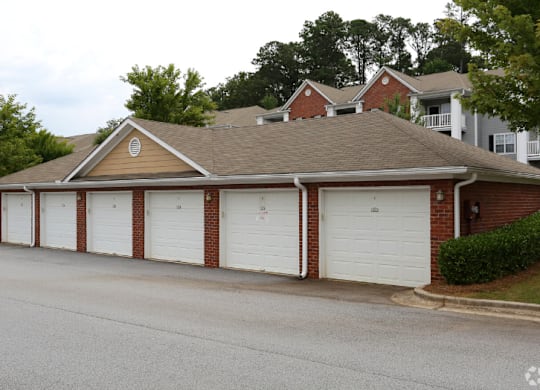 a garage with white doors in front of a house at Magnolia Lake Apartments, Carrollton, Georgia