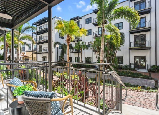 a balcony with chairs and palm trees in front of an apartment building at Casa Marti, Tampa, FL