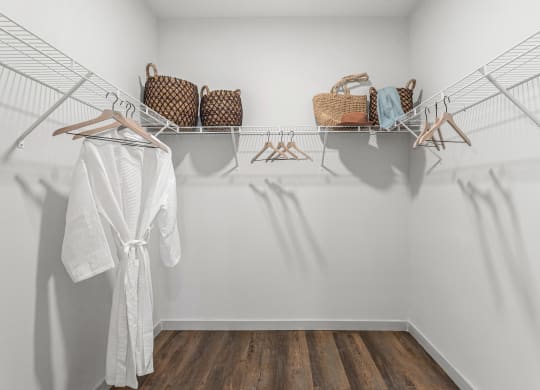 a closet with white walls and a white robe and baskets on the shelves at Casa Marti, Tampa, 33605