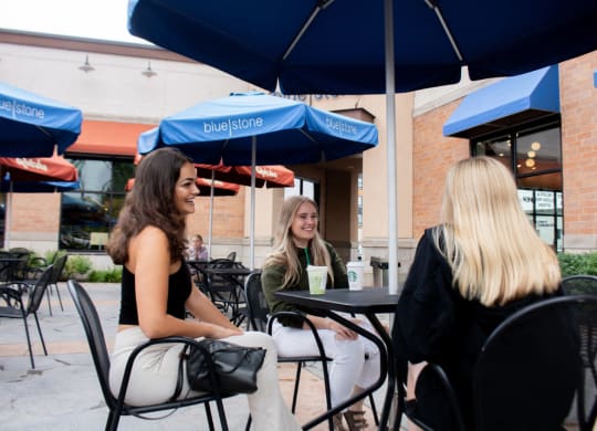 three women sitting at a table under an umbrella at Bluestone Lofts, Minnesota, 55803