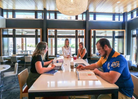 a group of people sitting around a table in a library at Bluestone Lofts, Minnesota, 55803