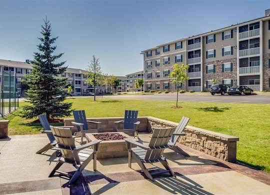 a patio with chairs and a fire pit in front of an apartment building  at Boulder Ridge, Duluth, MN 55811
