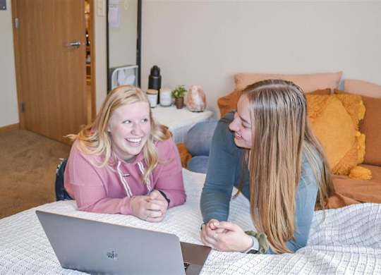 two women laying on a bed with a laptop at Boulder Ridge, Duluth, MN