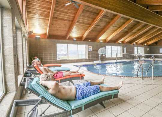 a man laying on a lounge chair next to a swimming pool at Boulder Ridge, Duluth
