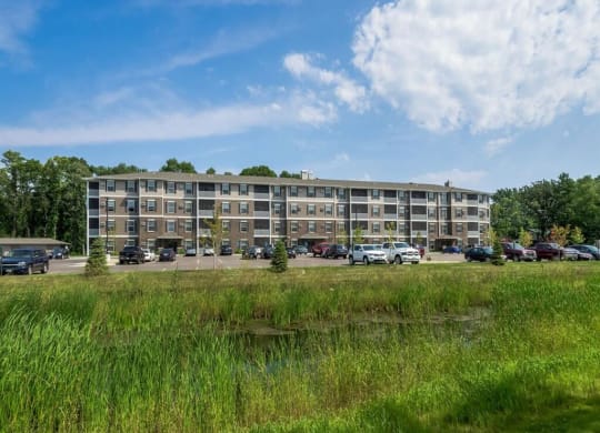 a large apartment building with cars parked in front of it at Arbor Ridge, Forest Lake, MN, 55025