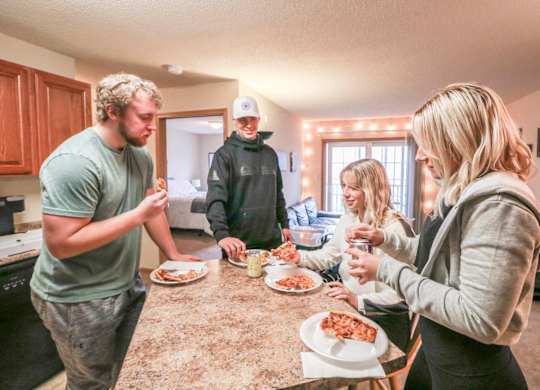people gathered around a kitchen counter eating pizza at Boulder Ridge, Duluth Minnesota