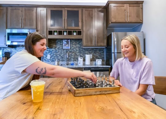 two women playing chess at a table in a kitchen  at Timber Ridge, Forest Lake