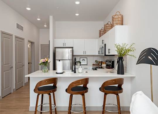 A kitchen with a white countertop and wooden bar stools.at Converge KC Uptown, Kansas City, MO 64111