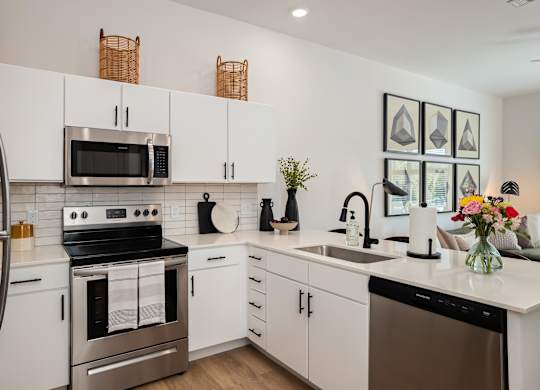 A modern kitchen with white cabinets and stainless steel appliances.at Converge KC Uptown, Missouri, 64111