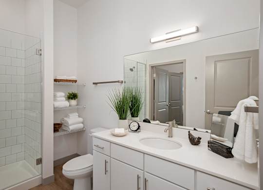 A white bathroom with a toilet, sink, and mirror.at Converge KC Uptown, Kansas City Missouri