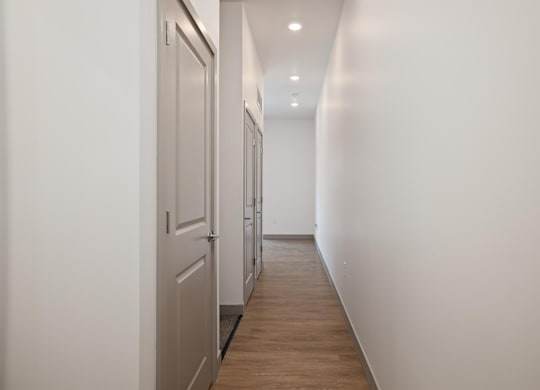 A long hallway with white walls and wood floors.at Converge KC Uptown, Missouri, 64111
