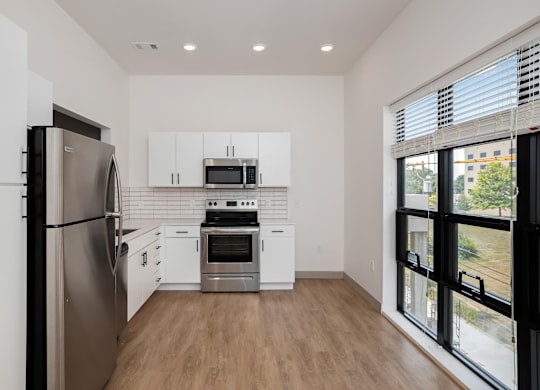 A modern kitchen with stainless steel appliances and white cabinets.at Converge KC Uptown, Kansas City Missouri